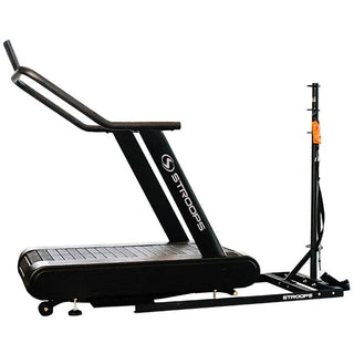 A black flat self-propelled motorless treadmill with a low-profile steel frame, slatted running belt, front support handles, and a vertical steel spine positioned behind the treadmill. The system can be configured with optional resistance training accessories including the Base Slastix® Adjustable Anchor, Universal Swivel Belt XL, and Optitail® Anchoring System for performance training and rehabilitation applications.