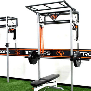 The Stroops PSTATION Performance Station is a sleek wall-mounted black fitness station with a vertical rack, multiple resistance band anchor points, adjustable J-hooks for Olympic barbells, and upper storage space for workout equipment. The compact station is designed for resistance, strength, and performance training for up to two users.