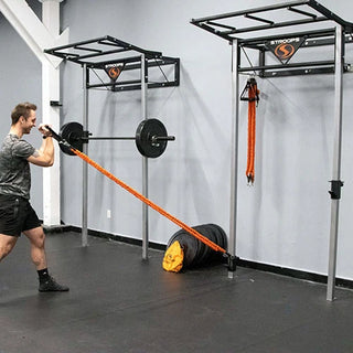The Stroops PSTATION Performance Station is a sleek wall-mounted black fitness station with a vertical rack, multiple resistance band anchor points, adjustable J-hooks for Olympic barbells, and upper storage space for workout equipment. The compact station is designed for resistance, strength, and performance training for up to two users.