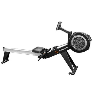 The Stroops SXR Xtreme Rower is a commercial rowing machine with a black flywheel housing, long aluminum monorail, ergonomic padded seat, adjustable footrests, and an angled padded handle. A user-friendly performance console is mounted above the flywheel, while integrated transport wheels and a foldable frame allow the rower to be moved and stored easily when not in use.