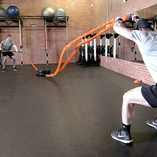 The Stroops SRPBASE Portable Base is a low-profile black octagonal steel ground anchor with eight evenly positioned connection points around its perimeter and a central area for adding weight plates. Its compact design is intended for portable group resistance training and floor-based exercises.
