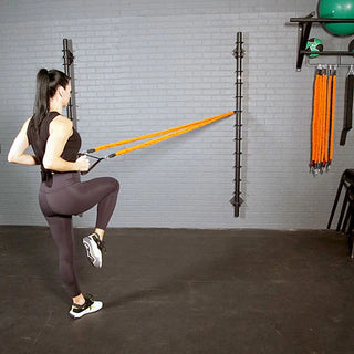 The Stroops Spine is a slim wall-mounted steel resistance band anchor with multiple horizontal anchor rings arranged vertically from high to low. The system is available in three configurations: a 78-inch version with 13 anchor points, a 48-inch version with 8 anchor points, and a slimmer 48-inch Mini with 8 anchor points.