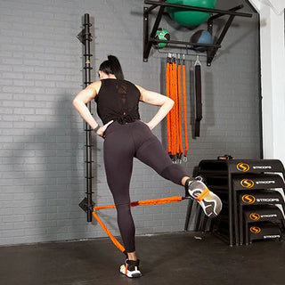 The Stroops Spine is a slim wall-mounted steel resistance band anchor with multiple horizontal anchor rings arranged vertically from high to low. The system is available in three configurations: a 78-inch version with 13 anchor points, a 48-inch version with 8 anchor points, and a slimmer 48-inch Mini with 8 anchor points.