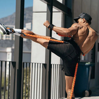 The Stroops Striker is a black resistance training suit with a training belt, limb resistance bands, punch gloves, and foot cuffs designed for full-body explosive movement training.