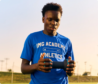Athlete gripping the Therabody CryoTherm Palm with both hands on a sports field