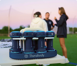 Several Therabody CryoTherm Palm units on a table at an outdoor training session