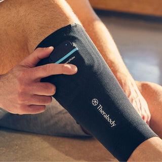 Seated man adjusting the control pod on the Therabody RecoveryPulse Calf sleeve he is wearing