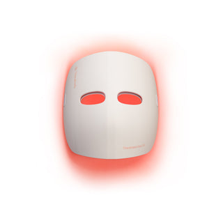 Therabody TheraFace Mask Glo light therapy mask glowing red against a plain background