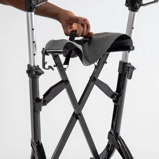 Black carbon fibre Triumph Mobility Maverick rollator walker with a padded seat, backstrap, ergonomic handgrips, integrated shopping bag, cup holder, cane holder, and large front wheels.