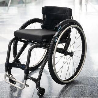 Pair of black reTyre Traction Skins attached over wheelchair tires with rugged tread and Velcro fasteners for improved traction on snow, slush, rain, grass, and gravel.