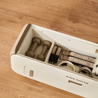 Open storage compartment of the WalkingPad B2 Pilates bench holding its accessories