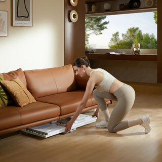 Woman unfolding the WalkingPad C1 Pilates board on a wooden floor