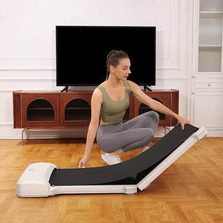 Woman kneeling to unfold the WalkingPad C1 walking machine in a living room