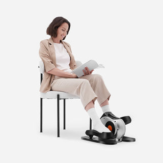Woman reading while pedalling the WalkingPad E1 under desk elliptical