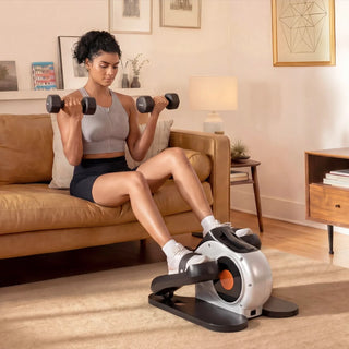 Woman lifting dumbbells while using the WalkingPad E1 elliptical at home