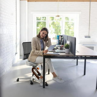 Woman on the WalkingPad FC1 office bike chair at a desk in an office