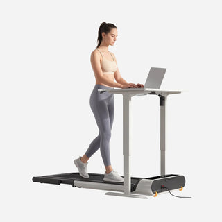 Woman walking on the WalkingPad MX3 treadmill with the handrail folded, working at a standing desk