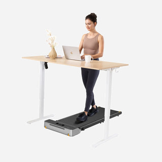 Woman walking on the WalkingPad Z1R treadmill beneath a standing desk
