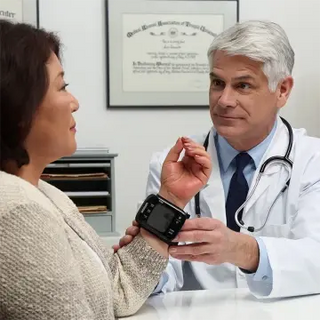 Doctor examining a patient's wrist with a omron 7 series blood pressure monitor, in a medical setting.